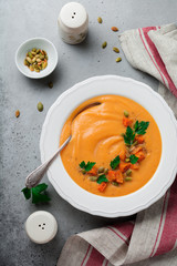 Homemade pumpkin soup in white ceramic dish on old gray concrete or stone background. Selective focus.  Top view. Copy space.