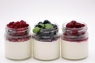 Fresh berries in the jar with the yogurt. On white background.