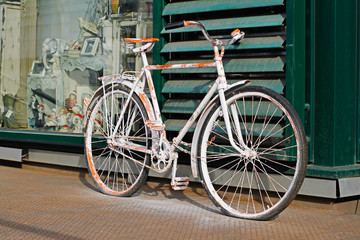 Naklejka na ściany i meble Shabby white bicycle standing near the shop outdoors
