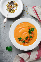 Homemade pumpkin soup in white ceramic dish on old gray concrete or stone background. Selective focus.  Top view. Copy space.