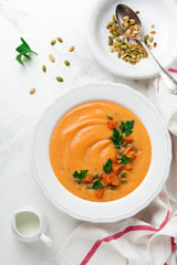 Homemade pumpkin soup in white ceramic dish on light concrete or stone background. Selective focus.  Top view. Copy space.