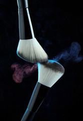 Makeup brush powder explosion on black background