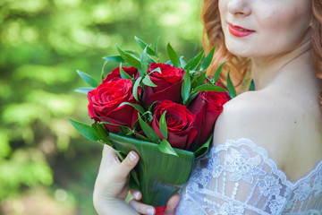 bride walking in the park in the summer. A bouquet in the hands of the bride. Wedding in red shades