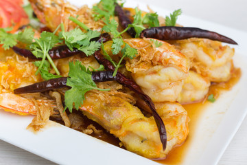 Fried shrimp with tamarind sauce in white dish on table.