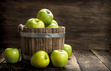 Green fresh apples in a wooden bucket.