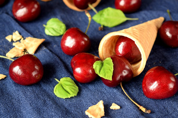 Waffle cones and cherries on blue background. Ingredients for a dessert cooking