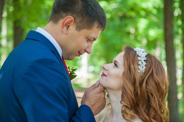 groom and bride on a walk in the park in the summer. Wedding in red shades