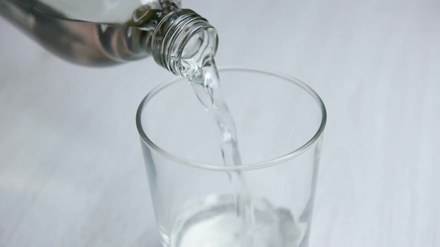 pouring natural water into glass from bottle. Shooting with circular motion