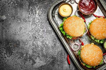 Street food. Fresh burgers with vegetables and sauces on a steel tray.