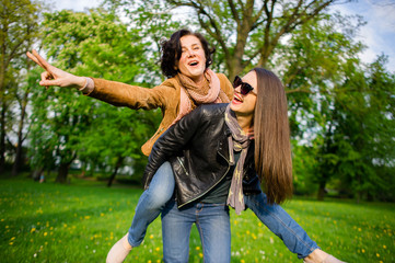 Two cute young women cheerfully spend time in the spring park