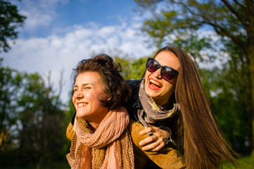 Two cute young women cheerfully spend time in the spring park