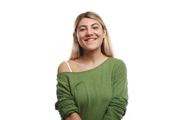 Horizontal shot of positive young European female student with nose ring and dyed hair posing in studio, looking at camera with happy charming smile, feeling relaxed after lectures at university