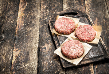 Raw burger from beef. On wooden background.