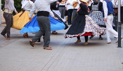 Local dancers in traditional dresses at a public Canarian festival with motion blur in San Sebastian, La Gomera