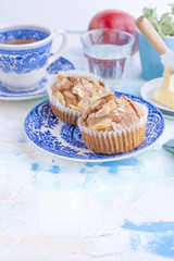 Homemade muffins with almonds on a blue plate for breakfast and tea in a cup. A glass of water and a red fresh apple and butter for sandwiches. Free place for text or postcard.