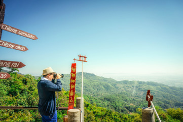 Man wearing a hat with binoculars on peak mountain view