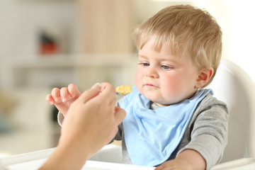 Mother hand feeding her baby in a high chair