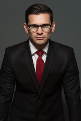 You're fired! An angry businessman in formal suit and glasses stands up from the table on gray background