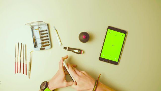 Green screen. Male hands reparing smartphone