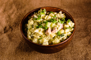 Ceramic bowl with russian traditional salad olivier on wooden table