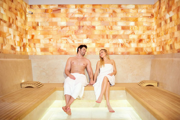 Couple in towels resting in the sauna. Man and woman in a spa salon.
