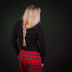 Woman with blond braid hairdo and red scottish trousers  in a cage.