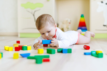 Cute baby girl playing with colorful rattle toys