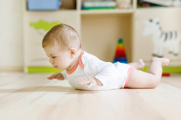 Naklejka premium Cute baby girl learning crawling and sitting in children room