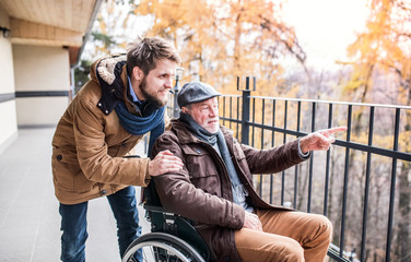 Senior father in wheelchair and young son on a walk.