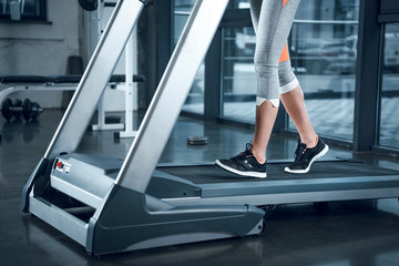 Obraz premium cropped shot of sportswoman running on treadmill at gym