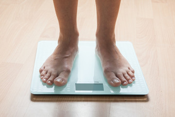 Healthy diet, fitness and weight loss concept. The legs of a young woman on the scales. Checking the weight.
