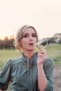 portrait of beautiful attractive blonde woman in retro dress smoking cigarette in the sunset outdoor 