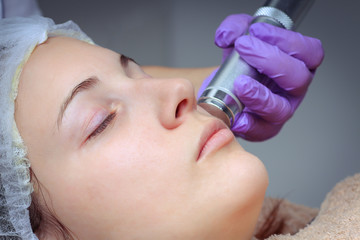 Needle mesotherapy. Beautician performs a needle mesotherapy treatment on a woman's face