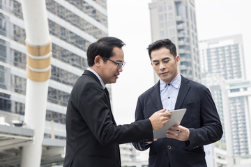 Fototapeta premium Businessman presenting work to boss, leader about planning project by laptop outside building.