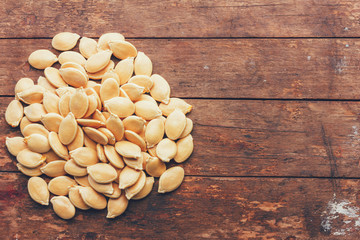 a bunch of pumpkin seeds on wooden retro grunge background, top view closeup with copy space