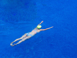 woman with bikini swimsuit swimming in a blue water swimming pool