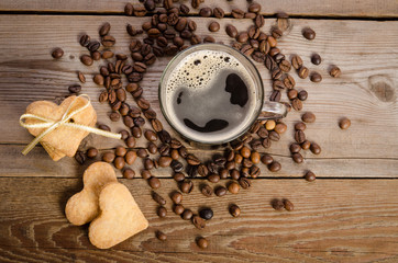 The cup of coffee, coffee beans and cookies-hearts related together on  wooden table