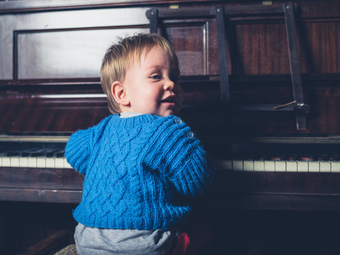 Cute little baby boy sitting by piano