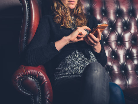 Woman on leather sofa using phone