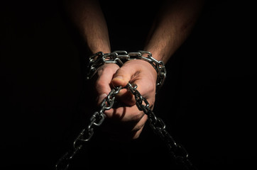 Hands are chained in chains isolated on black background