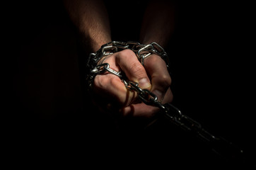 Hands are chained in chains isolated on black background