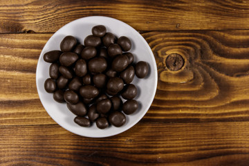 Peanuts coated with chocolate on wooden table