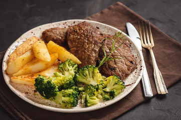 Grilled beefsteack with broccoli and  baked potatoes.