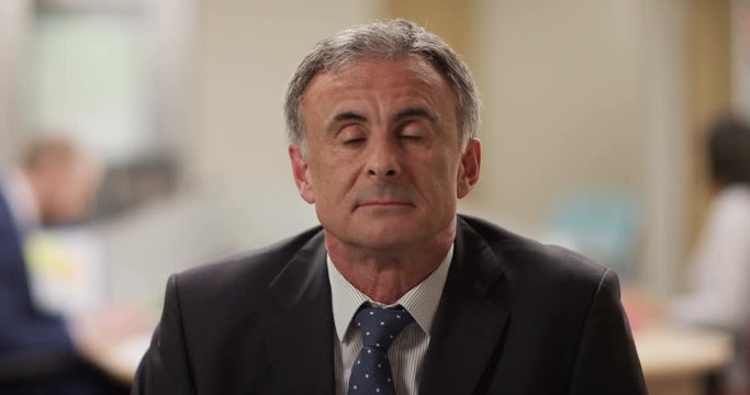 4K Mature businessman smiling & nodding during very boring conference call