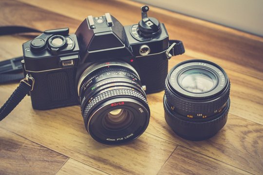 un ancien appareil photo avec un flash install&eacute; au milieu d'un fond en bois marron