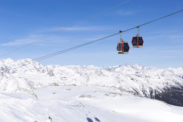 Fototapeta na wymiar Cableway lift cable cars, gondola cabins on winter snowy mountains background beautiful scenery.