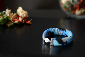 Blue beaded bracelet camouflage coloring on a dark background close up