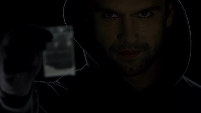 Drug baron offering dose to drug addict in darkness, selling narcotic substance