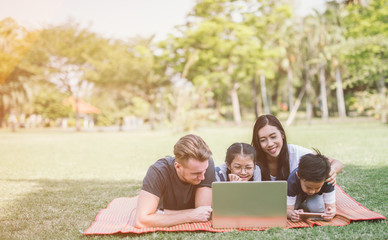 Modern family using laptop while resting in park