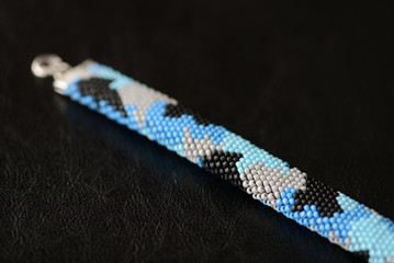 Blue beaded bracelet camouflage coloring on a dark background close up